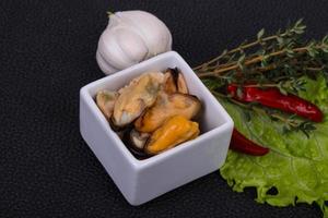 Pickled mussels in the bowl served pepper, garlic and salad photo