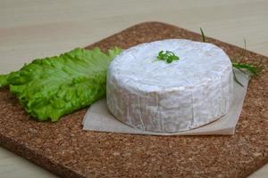 queso camembert sobre tabla de madera y fondo de madera foto