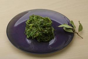 ensalada chuka en el plato y fondo de madera foto