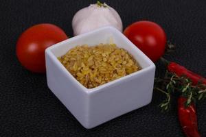 Raw bulgur in the bowl with tomatoes and garlic photo