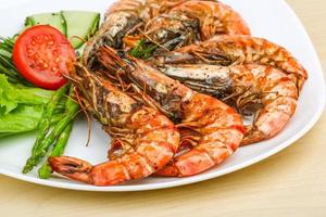 Grilled prawns on the plate and wooden background photo