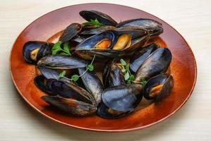 Boiled mussels on the plate and wooden background photo