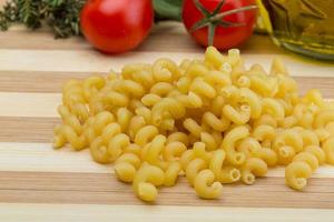 Cellentani pasta on wooden board and wooden background photo