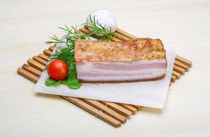 Raw bacon on wooden board and wooden background photo