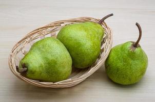Green pears in a basket on wooden background photo