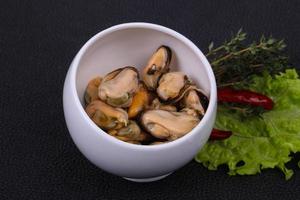 Pickled mussels in the bowl served pepper, garlic and salad photo