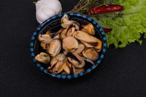 Pickled mussels in the bowl served pepper, garlic and salad photo