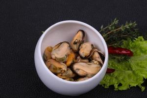 Pickled mussels in the bowl served pepper, garlic and salad photo