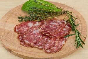 Salami on wooden board and wooden background photo