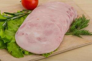 Sliced ham on wooden board and wooden background photo