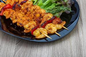 Prawn skewer on the plate and wooden background photo