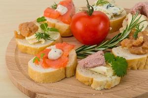 Assorted tapas on wooden board and wooden background photo