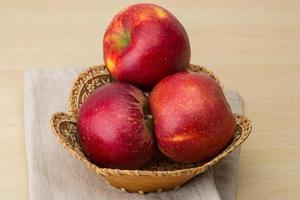 Red apples in a basket on wooden background photo