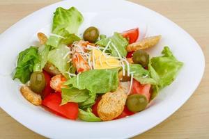 Caesar salad on the plate and wooden background photo