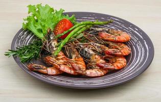 Grilled prawns on the plate and wooden background photo