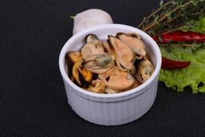 Pickled mussels in the bowl served pepper, garlic and salad photo