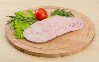 Sliced ham on wooden board and wooden background photo