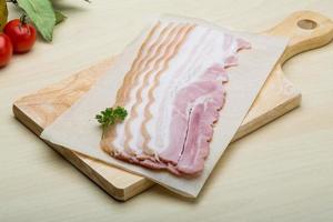 Raw Bacon on wooden board and wooden background photo