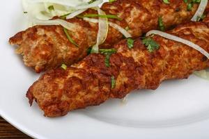 kebab de ternera en el plato y fondo de madera foto