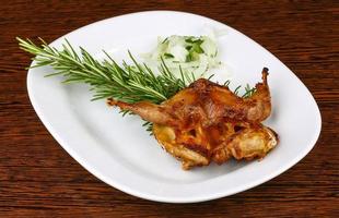 Grilled quail on the plate and wooden background photo