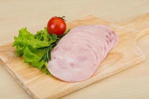 Sliced ham on wooden board and wooden background photo