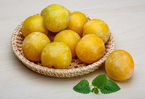 Yellow plums on wooden board and wooden background photo