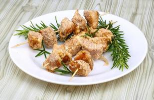 Chicken skewers on the plate and wooden background photo