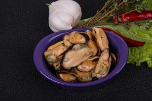 Pickled mussels in the bowl served pepper, garlic and salad photo