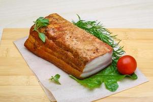 Raw bacon on wooden board and wooden background photo