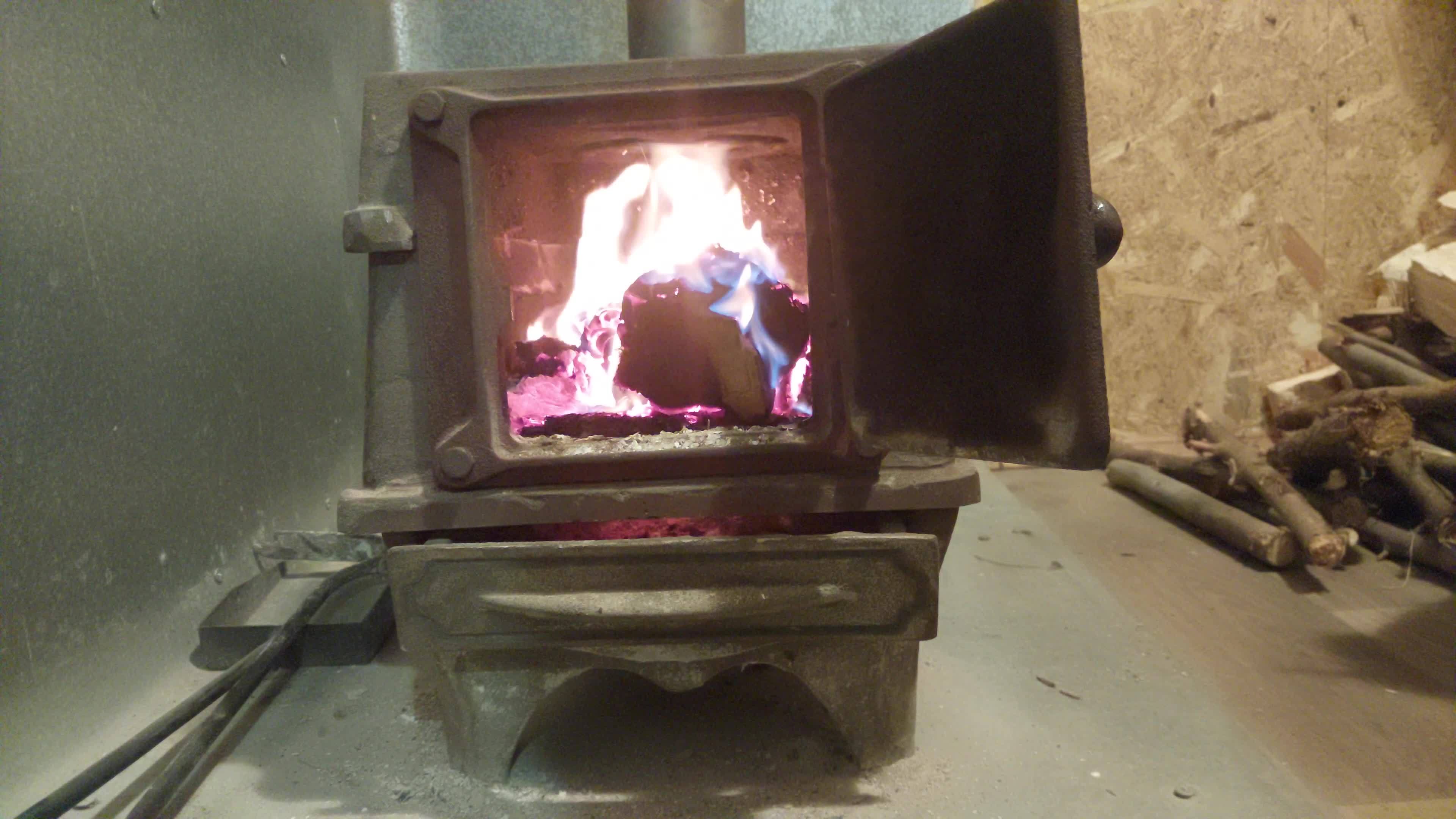 Firewood burning in a castiron stove warming the house 12286468 Stock