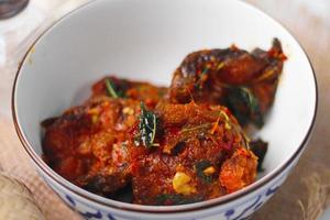 Spicy Stir Fried Catfish served in a Thai style patterned bowl on a white table. photo