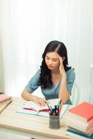 Focused school girl studying with books preparing for test exam writing essay doing homework at home photo