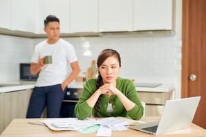 Upset young man with financial bills having conflict with woman at home photo