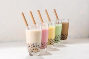 Colorful selection of milky fruit flavored bubble tea arranged in a line on white background photo