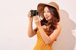 Attractive young woman with a photo camera in her hand on an isolated beige background. The concept travel