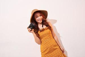 imagen de una joven fotógrafa aislada sobre una pared de fondo beige sosteniendo una cámara. foto
