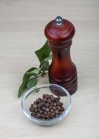 Pepper mill on wooden background photo