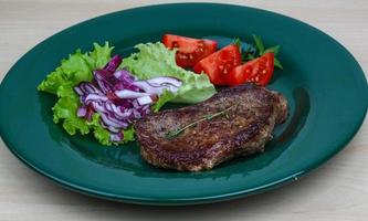 Beefsteak on the plate and wooden background photo