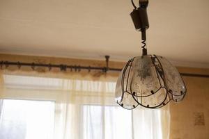 Chandelier in old interior. Lamp in room. Light from window. photo