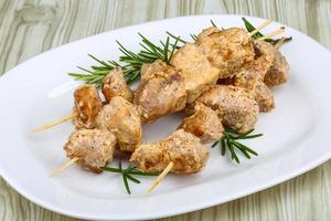 Chicken skewers on the plate and wooden background photo