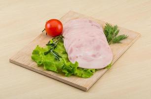 Sliced ham on wooden board and wooden background photo