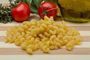 Cellentani pasta on wooden board and wooden background photo