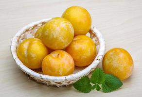 Yellow plums in a basket on wooden background photo