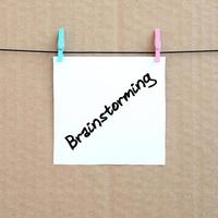 Brainstorming. Note is written on a white sticker that hangs with a clothespin on a rope on a background of brown cardboard photo