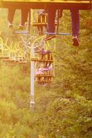 People ride on a cable car. The legs of passengers hang over the mountain forest photo