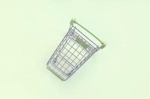 Small shopping cart lies on a lime background. Minimalism flat lay photo