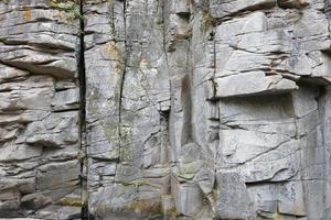 fondo de piedra de roca natural gruesa y clara. superficie frontal rugosa del acantilado minero. gran pila de piedra caliza como telón de fondo. textura de bloque de granito dañado grunge pesado foto