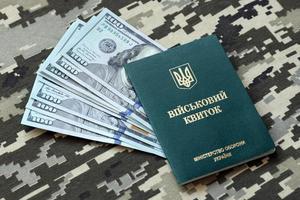 Ukrainian military ID and US dollar bills on fabric with texture of pixeled camouflage. Cloth with camo pattern in grey, brown and green pixel shapes with Ukrainian army personal token. photo