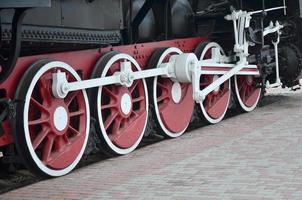 ruedas de la vieja locomotora de vapor negra de la época soviética. el lado de la locomotora con elementos de la tecnología giratoria de trenes antiguos foto