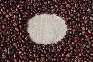 Texture of a gray canvas made of old and coarse burlap with coffee beans on it photo